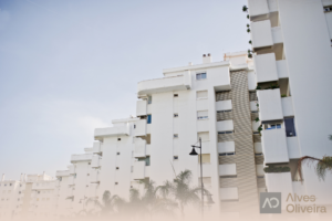 Fachada de edifício residencial urbano moderno com acabamento branco, ilustrando a segurança patrimonial e a rentabilidade de imóveis