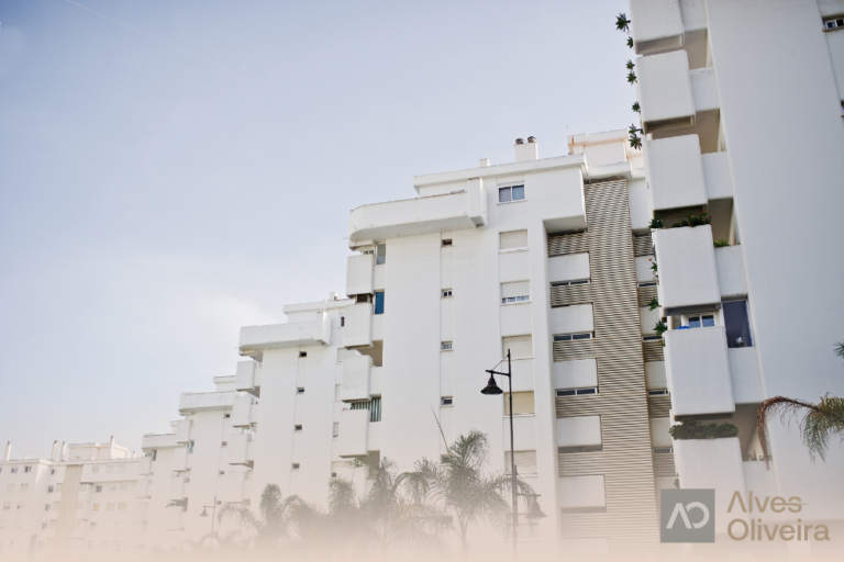 Fachada de edifício residencial urbano moderno com acabamento branco, ilustrando a segurança patrimonial e a rentabilidade de imóveis